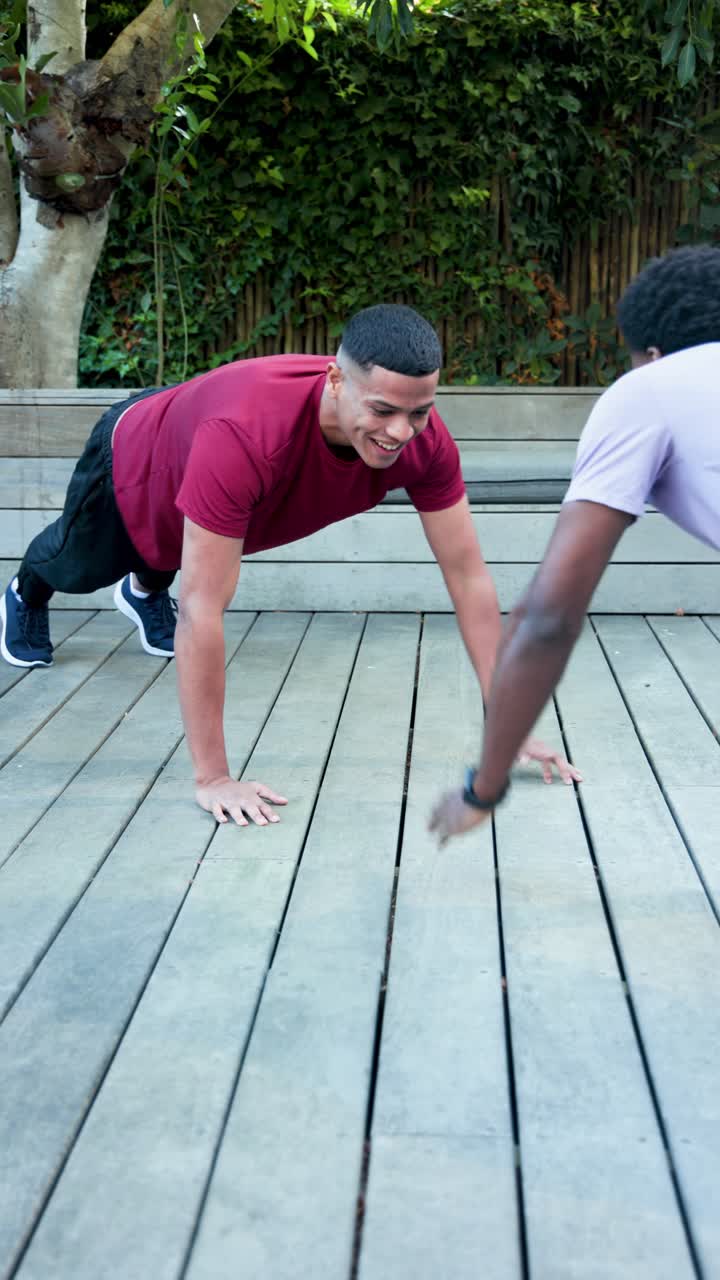 Video verticale: diversi amici di sesso maschile che fanno plank su una terrazza, si danno il cinque per caricarsi e poi si stringono la mano