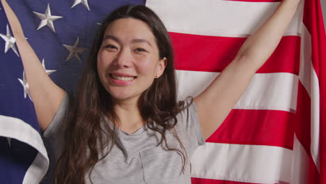 studio portrait shot of woman wrapped in american flag celebrating 4th july independence day 1