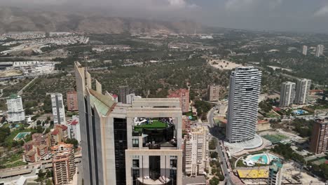benidorm, spain: drone pans right, showcasing the expansive cityscape and iconic skyline with the prominent gran hotel bali, a popular mediterranean tourist destination.