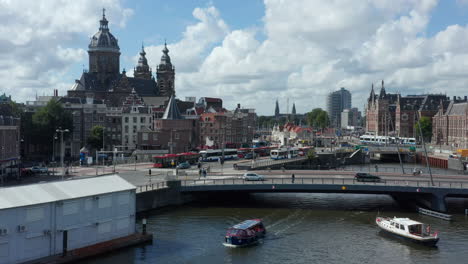 Towards-Basilica-of-Saint-Nicholas,-Amsterdam-over-River-with-Boat,-Aerial-Drone