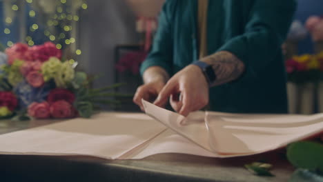 florist puts on table wrapping paper and cuts it