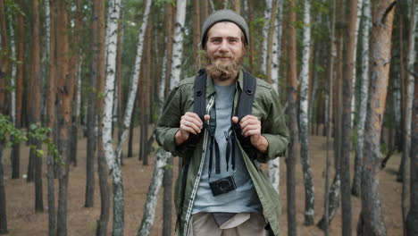 hombre caminando en el bosque con mochila y cámara
