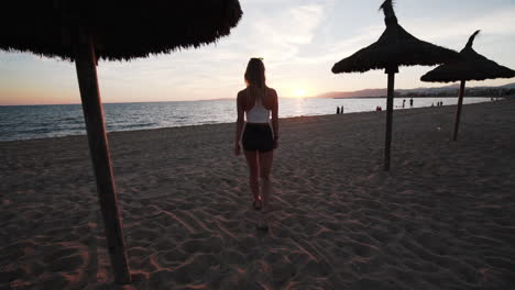 Chica-Está-Caminando-Al-Atardecer-En-La-Playa-De-Mallorca