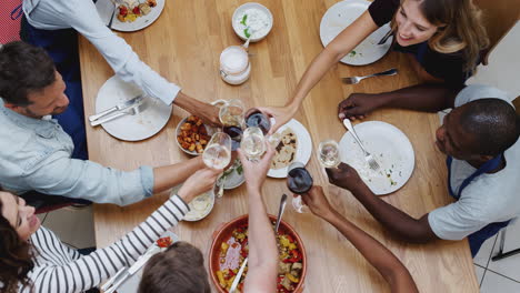 overhead shot of men and women making toast as they eat meal prepared in kitchen cookery class