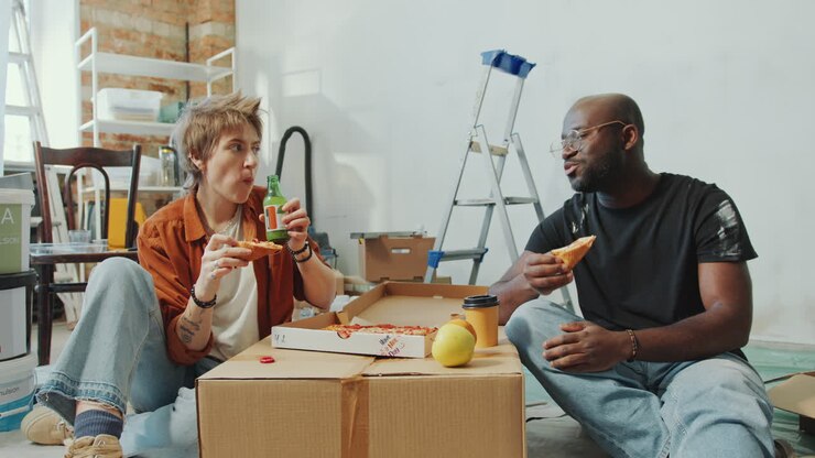 Couple Eating Pizza, Having Drinks and Talking on Break during Home Renovation