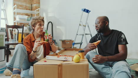couple eating pizza, having drinks and talking on break during home renovation
