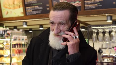 an elderly man with a beard on the phone indoors