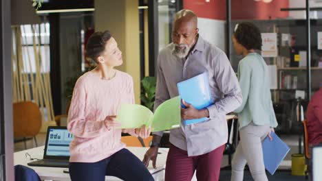 happy diverse business people holding documents and discussing work at office