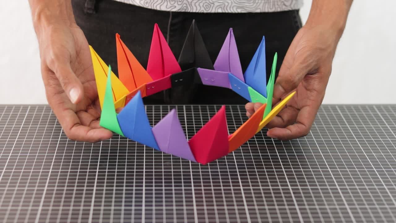 다채로운 무지개 종이를 보여주는 손 손으로 만든 왕관, 공예