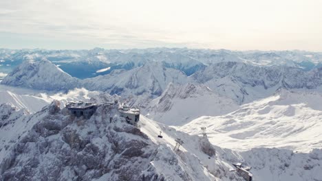 aerial approching summit of a snowy mountain while the cable car gondola comes in