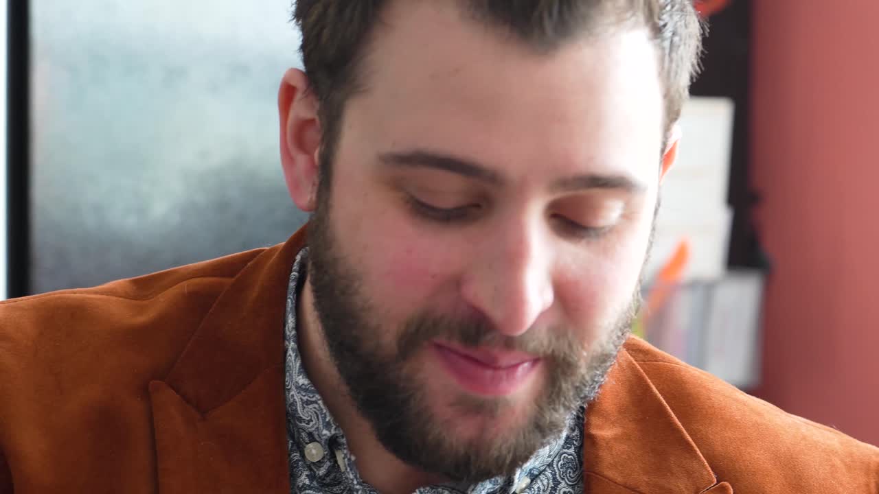 un hombre guapo con cara barbuda bebe un trago mientras oculta el vaso con la mano en el bar