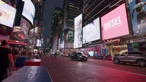 a busy night scene in times square with a city bus passing by neon lights and billboards