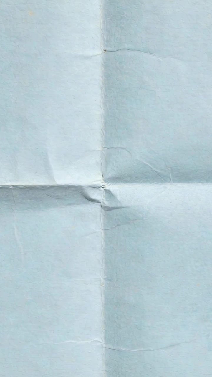 Vertical video: Starting camera filming pale bluish sheet in studio to document cross-fold crumple