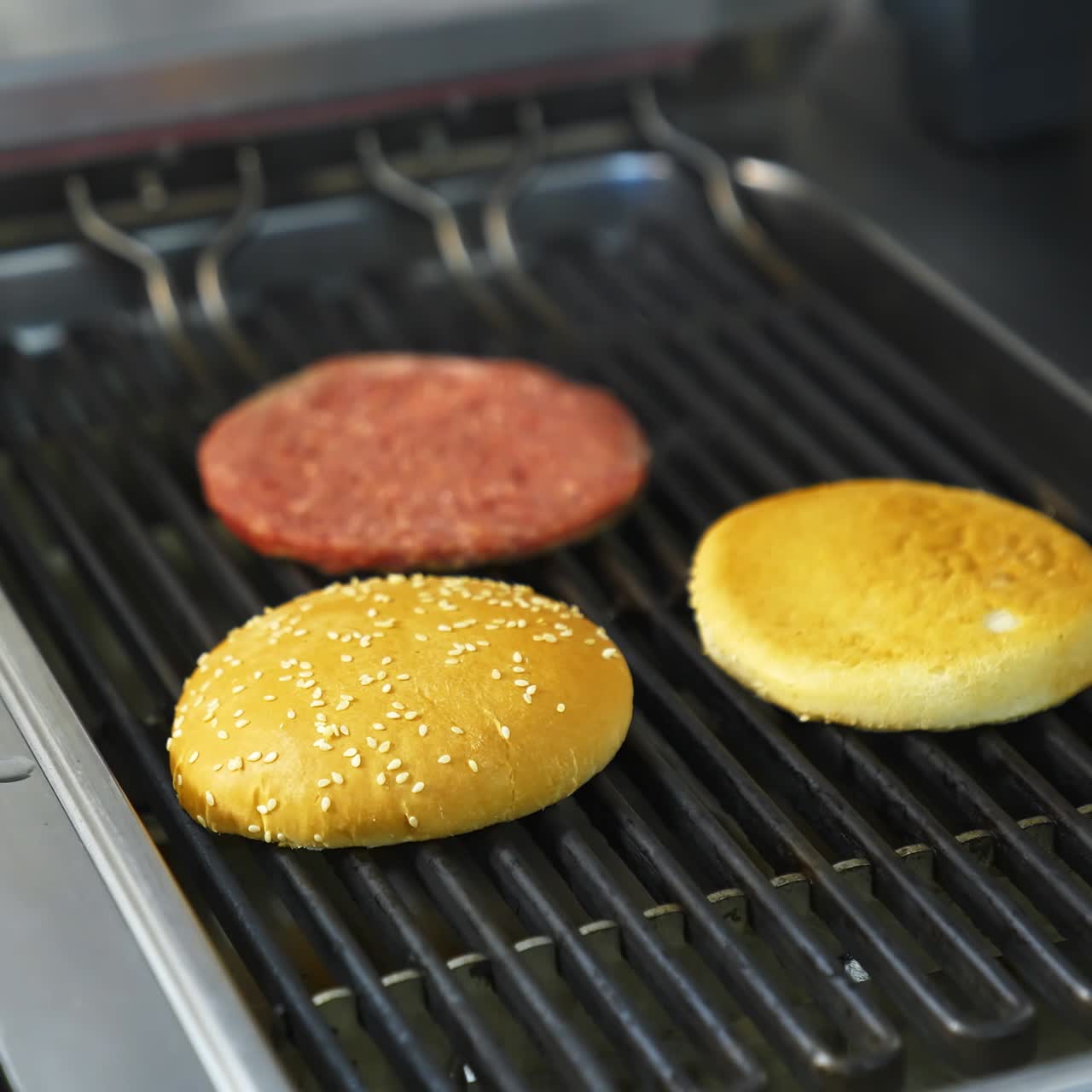 Fresh buns and raw cutlet are grilled on a barbeque. Selective focus on frying process
