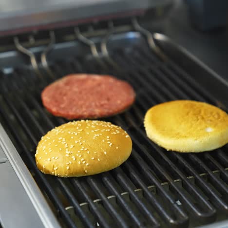 fresh buns and raw cutlet are grilled on a barbeque. selective focus on frying process