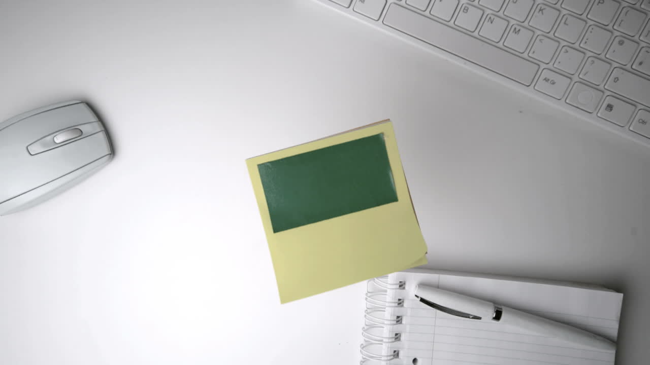 Yellow post it with green copy space falling on office desk