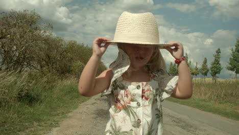 little girl playing with a big hat