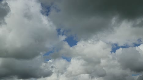 Cumulonimbus-Wolkensystem,-Das-Sich-Von-Links-Nach-Rechts-Bewegt,-Mit-Dunklen-Und-Hellen-Wolkenformationen-Und-Fleckigem-Blauen-Himmel