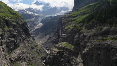 toma cinematográfica de drones de montañas cerca de grindelwald, en los alpes berneses de suiza, volando hacia una cascada