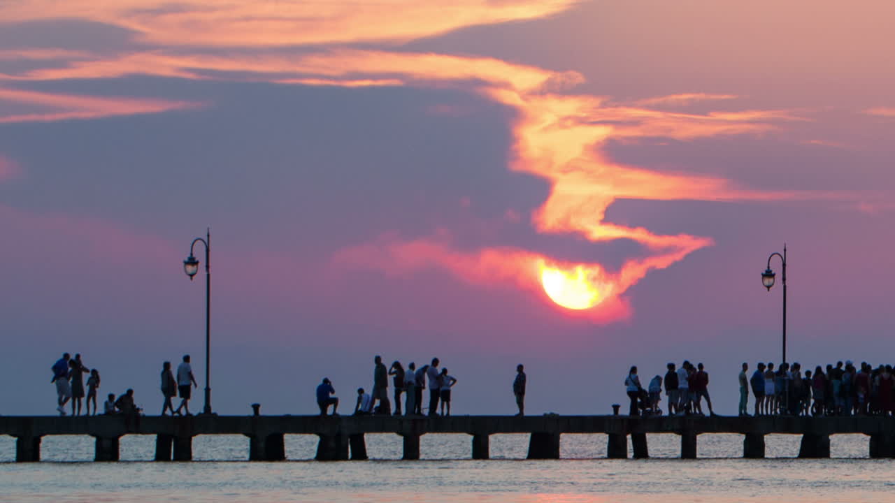 Timelapse of people walking on pier at sunset