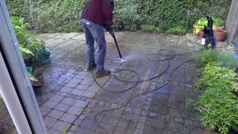 persona lavando piedras de jardín con un lavado a alta presión.