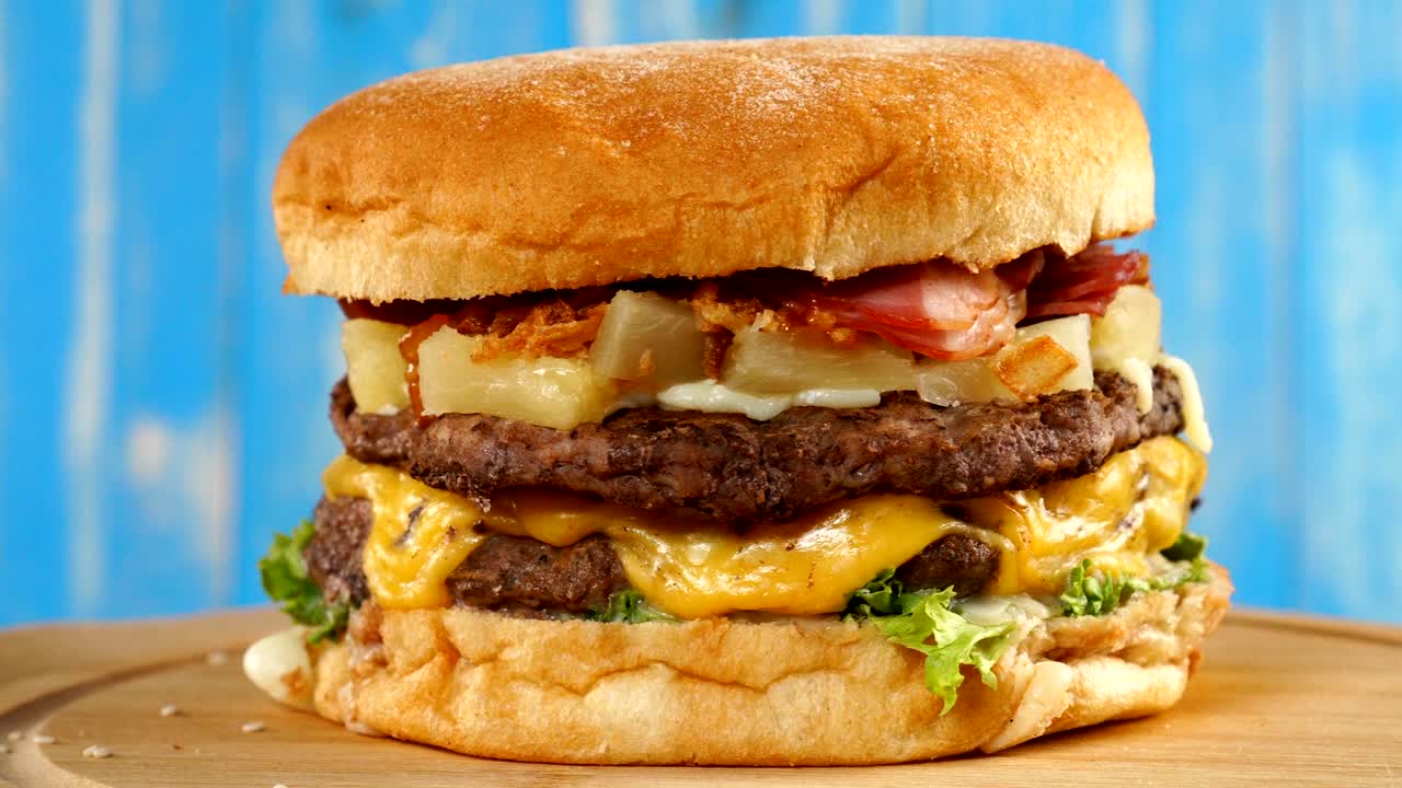 una hamburguesa fresca y apetitosa girando sobre un fondo azul.