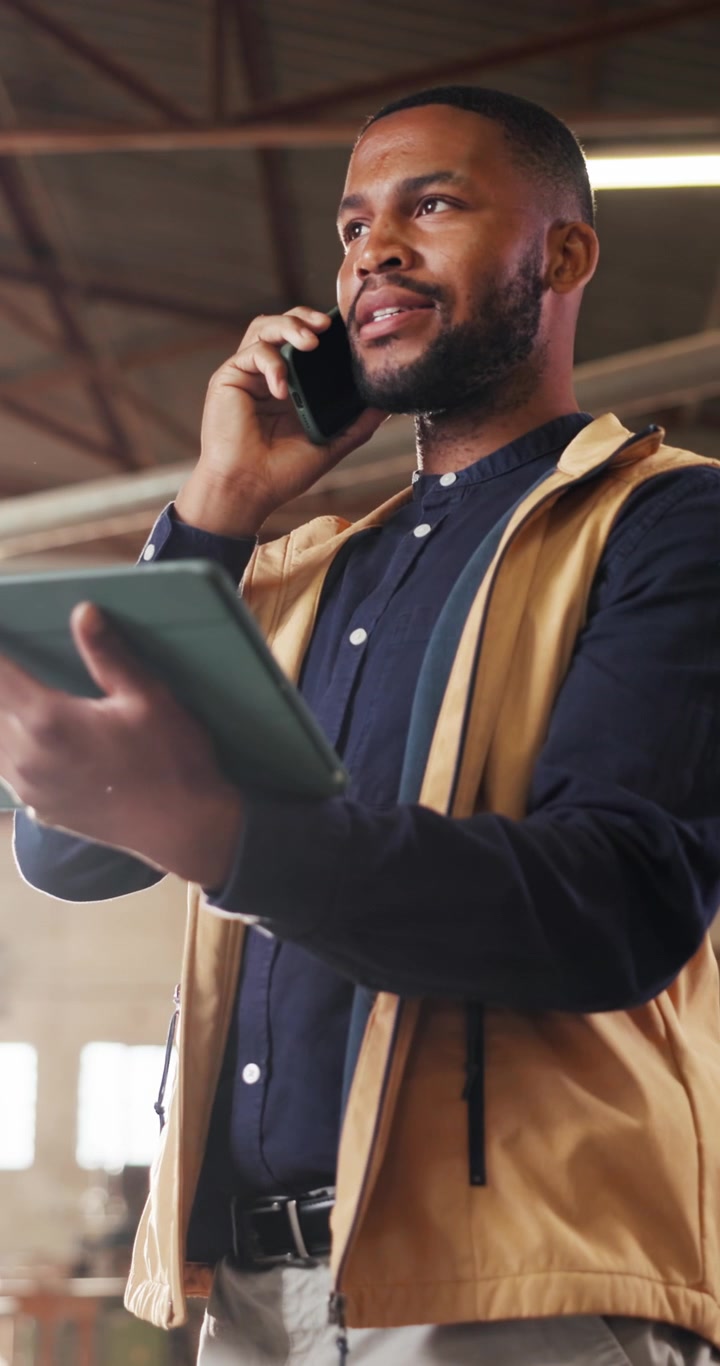 Professional Man Talking on Phone and Using Tablet in Warehouse