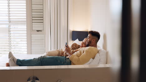 pareja relajándose en la cama, viendo un teléfono