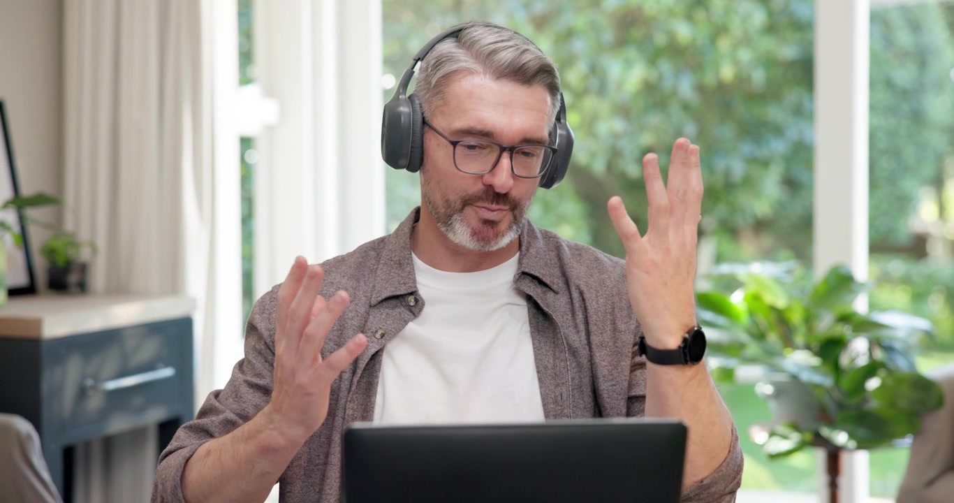 Hombre de mediana edad haciendo una videollamada en su portátil en casa