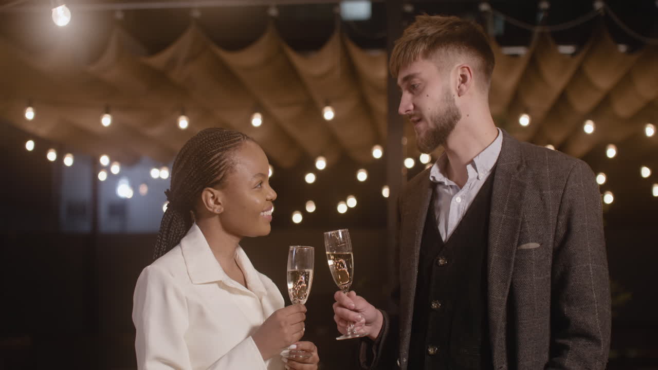 Man And Woman Holding Champagne Glasses And Talking To Each Other At New Year's Eve Party 1