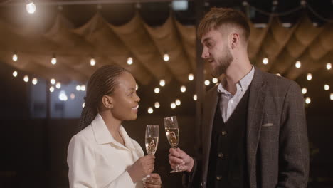 man and woman holding champagne glasses and talking to each other at new year's eve party 1