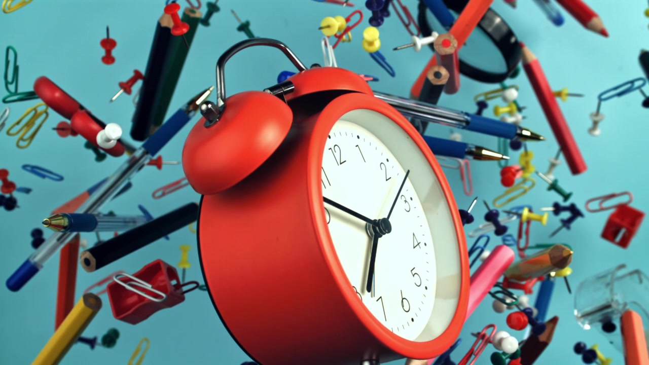 Time Passing on Red Alarm Clock with Floating Office Supplies