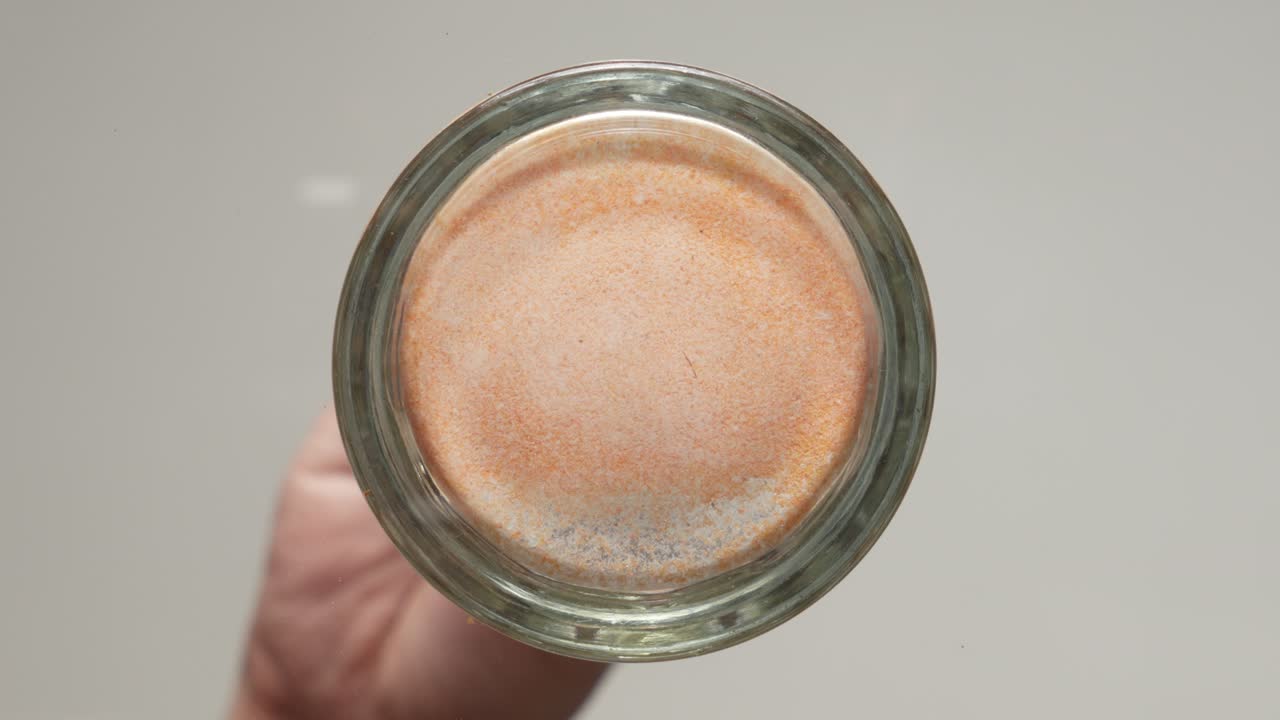 una persona vertiendo jugo en polvo en un vaso transparente. disparo de primer plano