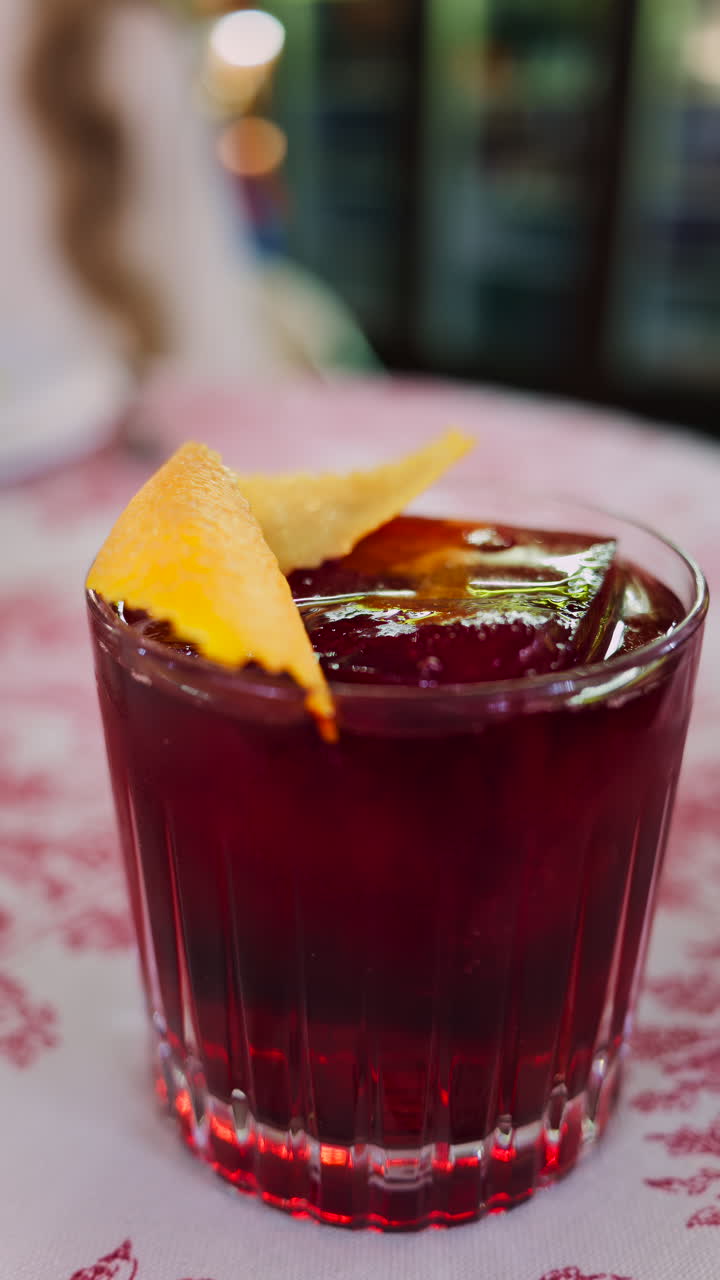 Primo piano di un cocktail negroni su una tovaglia a scacchi rossa e bianca in un ristorante. Verticale