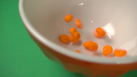 Lateral-view-of-orange-skulls-shaped-candy-falling-on-a-plate