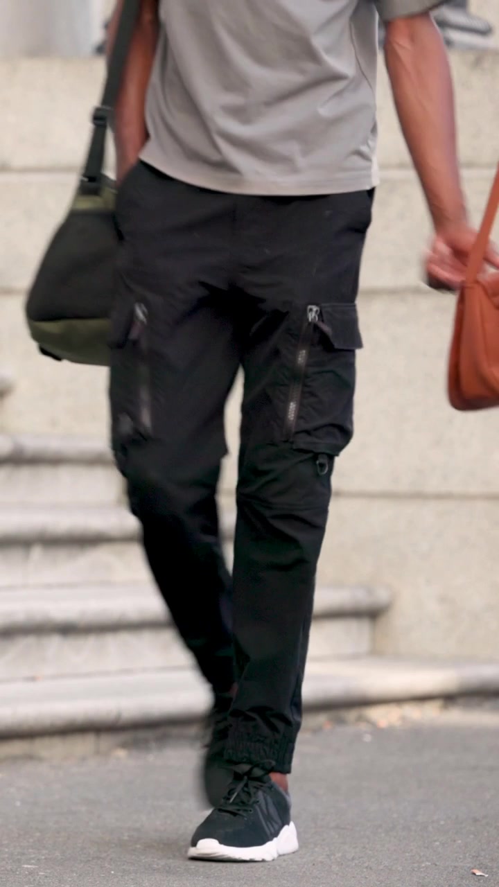 Vertical video: Arm entering, woman in tank top jeans walking with bottle past steps, copy space