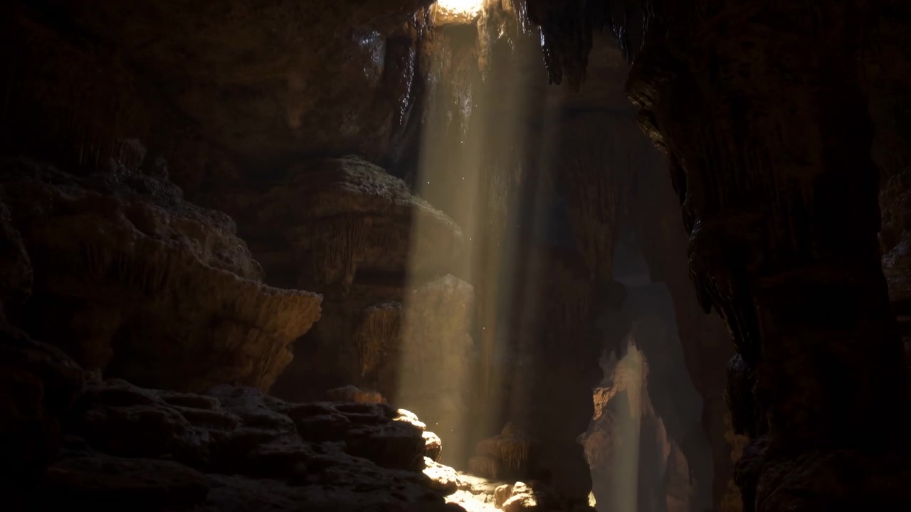 Warm sunlight penetrates small circular opening in cave ceiling, descending onto rocky ledges and textured floor while drifting dust glows in bright contrast against dark cavern walls