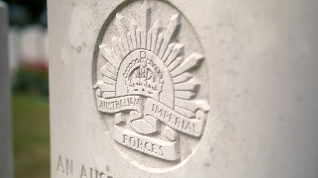 primer plano de una tumba de lápida australiana en un cementerio conmemorativo de la guerra entre un hermoso jardín verde con rosas rojas en ypres beglium, tiro de mano deslizante
