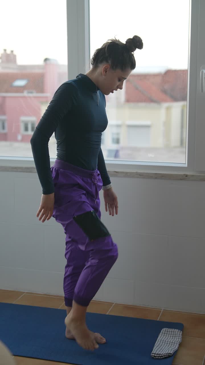 Mulher fazendo exercícios de yoga junto à janela