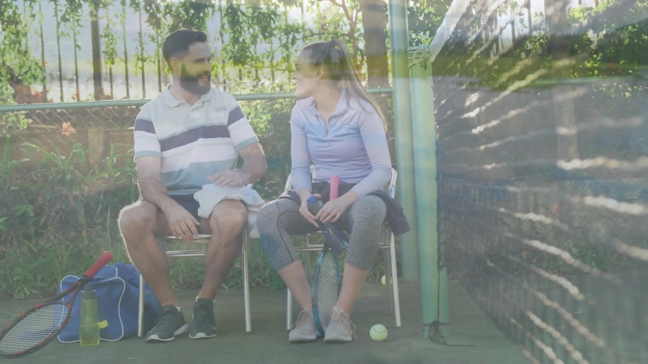 Composite video of diverse couple talking after playing tennis on the tennis court against mountains