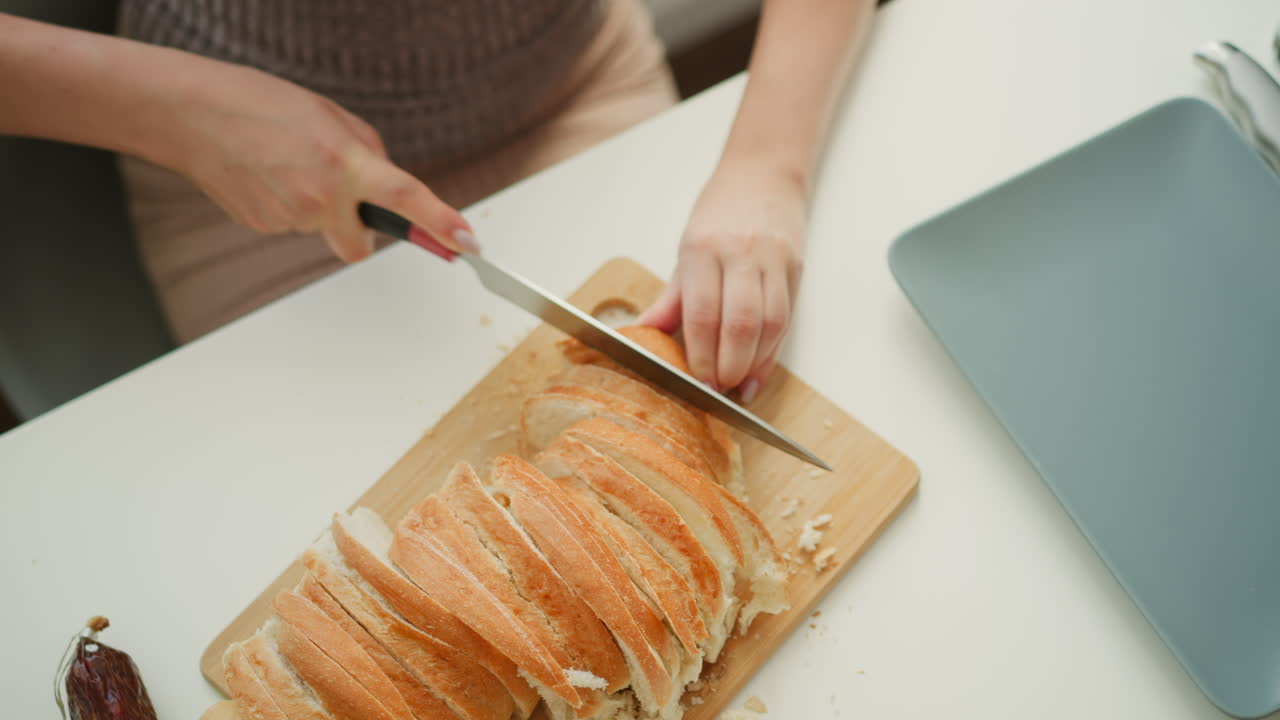 Close up of chef hands holding firm baked cake and cutting with knife gently slicing into equal parts on neat white table under bright morning light, highlighting texture of crust