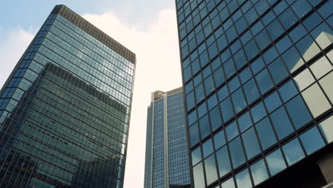 modern walls are made of glass and steel with reflections of buildings and blue sky