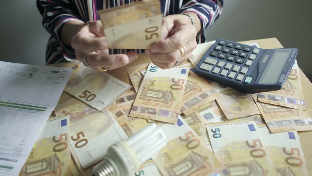 офисный стол, полный евро, наличные деньги, оплачиваемые руки, подсчет счетов рядом с калькулятором, концепция долга кредитной карты.