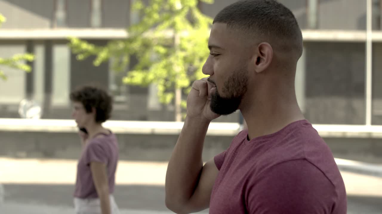 Uomo barbuto sorridente che parla allo smartphone mentre cammina