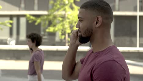 smiling bearded man talking on smartphone while walking