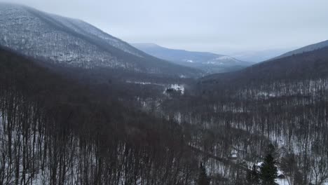 Fliegen-über-Ein-Schneebedecktes,-Wunderschönes-Bergtal-Mit-Einer-Abgelegenen-Straße-Darunter