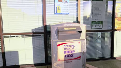 hispanic man votes in election by dropping mail-in ballot letter in slot at voting booth with offical ballot drop box sign for democratic government campaign in presidential race