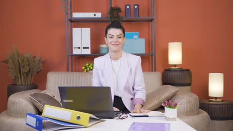 Home-office-worker-young-woman-smiles-at-camera.