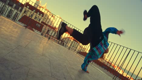 professional young adult woman in stylish clothes actively breakdancing on the street of an old town in a city. scene shot in an urban environment in ancient cultural tourist location.