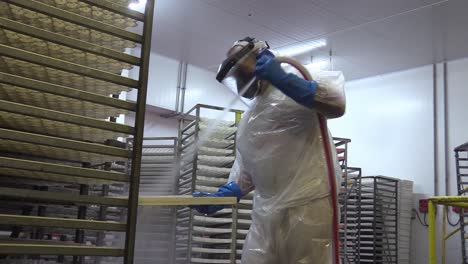 trabajador con traje de higiene epi limpiando tazas de huevo donde las gallinas ponen huevos en un gallinero industrial